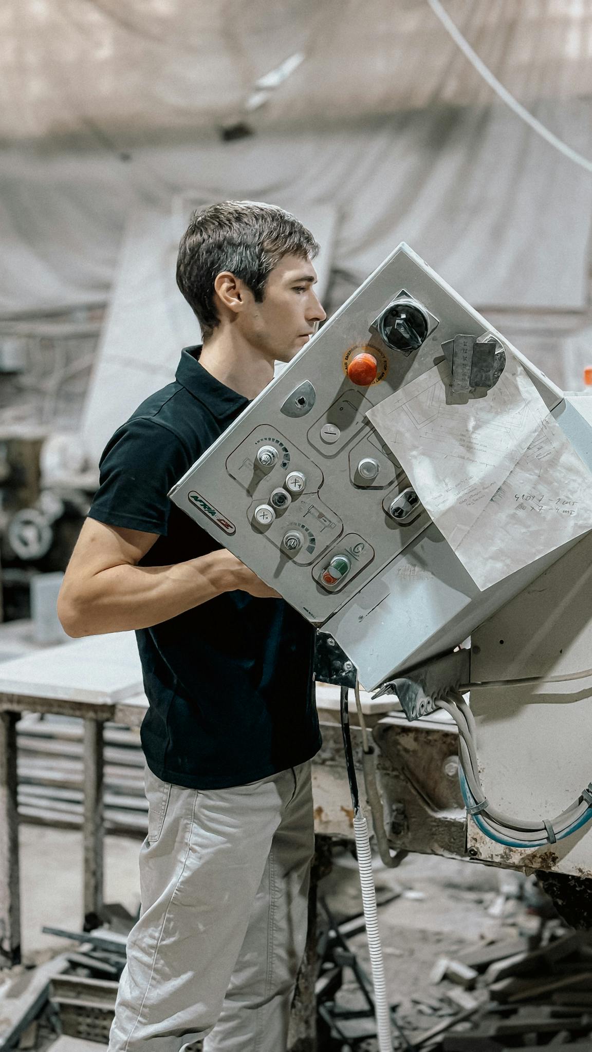 Focused young man operating complex machinery in an industrial setting.